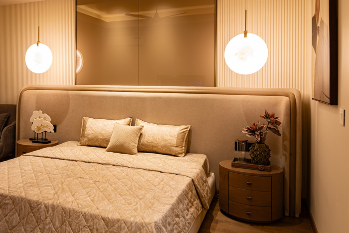 Spacious Casa Homes master bedroom designed with minimalistic elegance, floor-to-ceiling beige curtains, wall-mounted TV, and warm lighting.