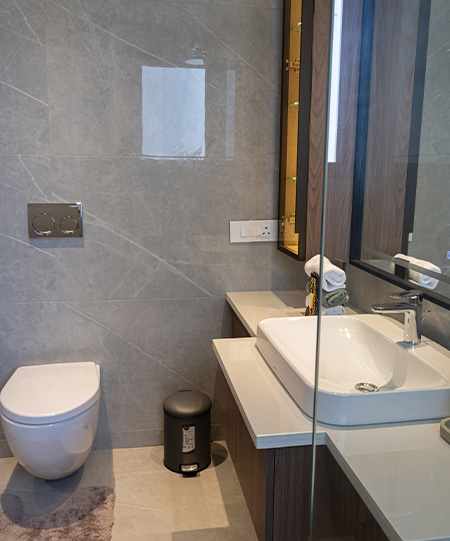 Casa Homes luxury bathroom with a floating vanity, backlit mirror, and beige marble wall tiles creating a serene spa-like environment.